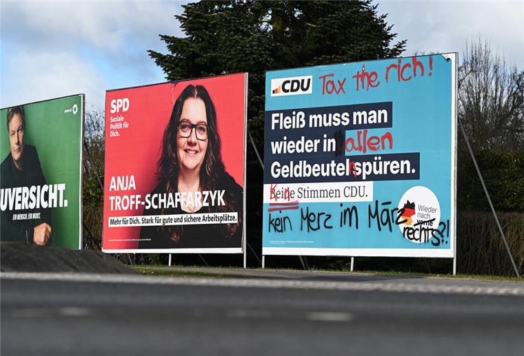 Ein beschmiertes Wahlplakat der CDU (r) steht an einer Straße