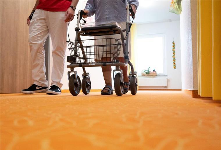 Forderung: Pflegekräfte sollen 4000 Euro Einstiegsgehalt kriegen Ein Betreuer geht in einem Pflegeheim mit einer Bewohnerin über den Flur.