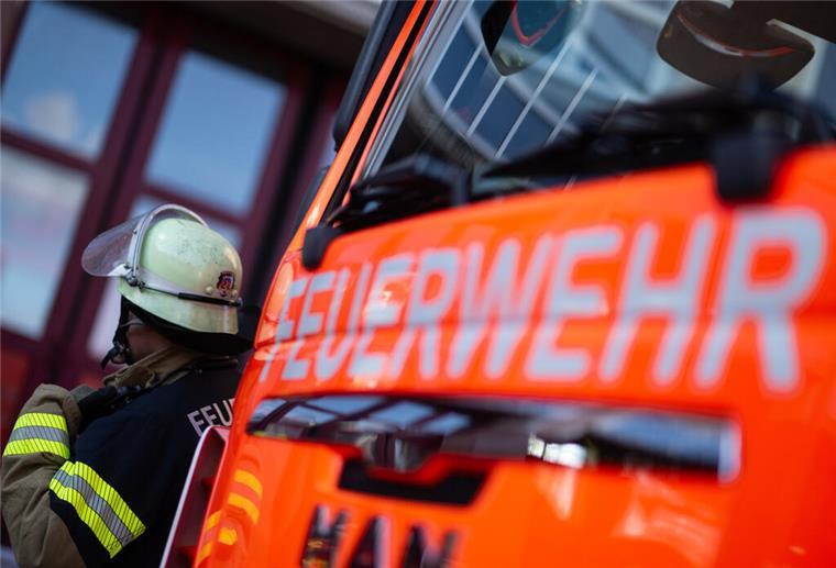 Eine Einsatzkraft der Feuerwehr steht neben einem Einsatzfahrzeug der Feuerwehr.