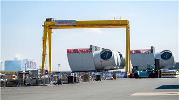 Ein Containerschiff fährt an den Offshore-Maschinenhäusern auf dem Werkgelände von Siemens Gamesa in Cuxhaven vorbei.