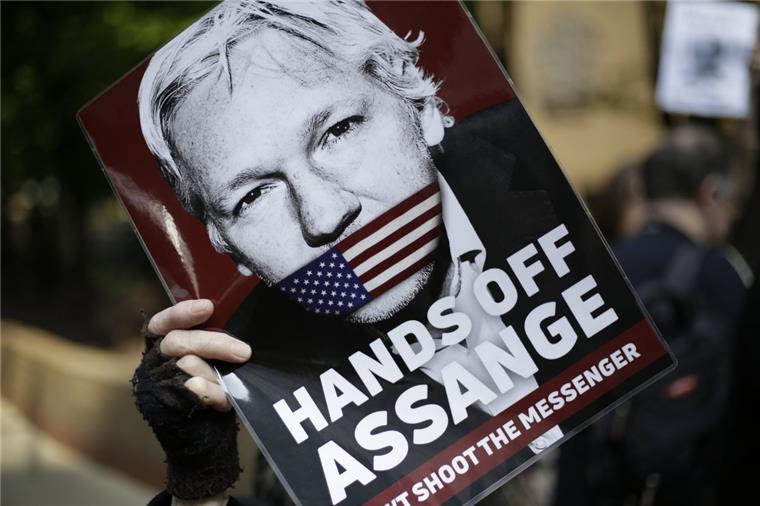 Wikileaks-Gründer Assange zu 50 Wochen Gefängnis verurteilt Ein Demonstrant hält ein Schild mit dem Porträt des Wikileaks-Gründers Assange in die Luft.