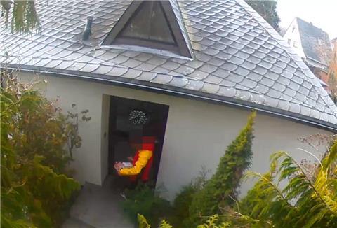 Ein Foto eines DHL-Boten vor einem Hauseingang.