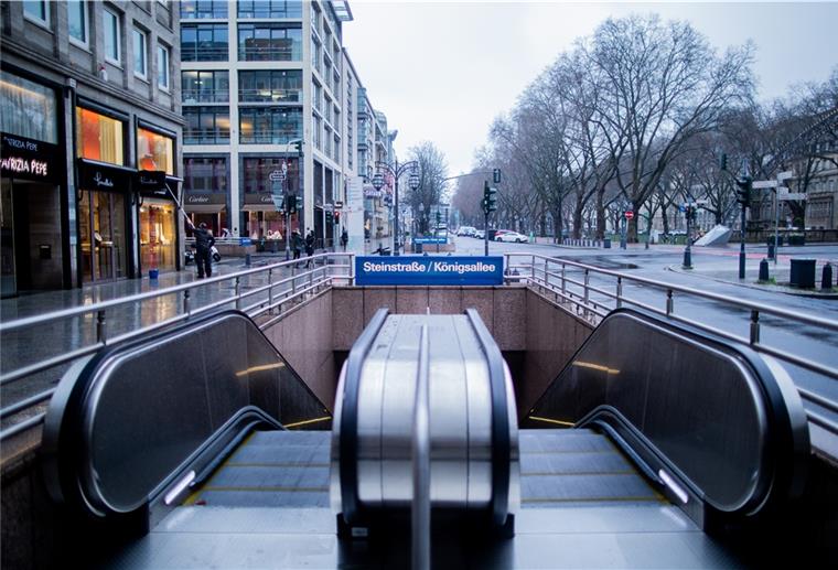 Nur wenige Menschen laufen bei Regen über die Königsallee in Düsseldorf