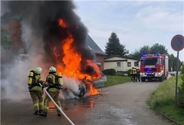 Ein Auto brennt in Nesse, während die Feuerwehr Löscharbeiten durchführt.