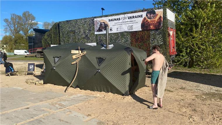 Sauna-Debattenfestival in Kulturhauptstadt Tartu Ein Festival-Besucher steht vor einer mobilen Front-Sauna, die in Estland für die ukrainische Armee entwickelt worden ist.