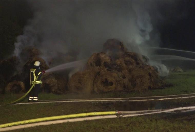 Landkreis Friesland: Feuer zerstört 500 Strohballen Ein Feuerwehrmann löscht brennende Strohballen.