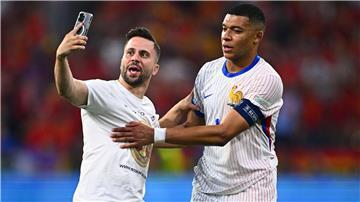 Ein „Flitzer“ ist aufs Spielfeld gelaufen und macht ein Selfie mit Frankreichs Kylian Mbappe (r).