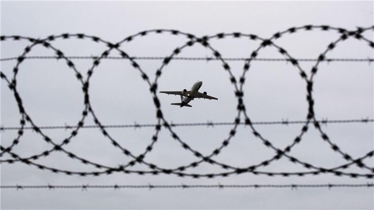Mehr Menschen aus Niedersachsen und Bremen abgeschoben Ein Flugzeug startet am Flughafen Hannover - fotografiert durch Stacheldraht am Flughafenzaun.