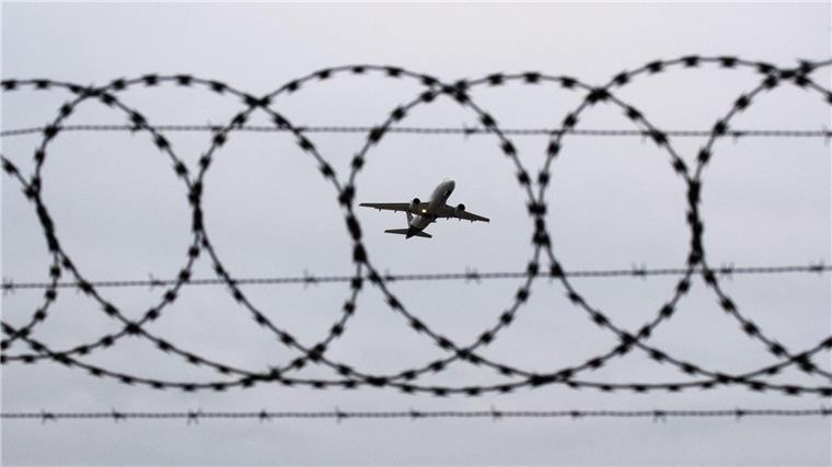 Niedersachsen verhängt Abschiebestopp für Jesiden Ein Flugzeug startet am Flughafen Hannover - fotografiert durch Stacheldraht am Flughafenzaun.