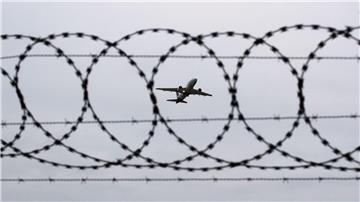 Ein Flugzeug startet am Flughafen Hannover - fotografiert durch Stacheldraht am Flughafenzaun.