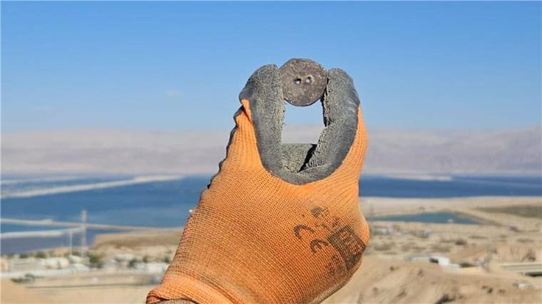 Pyramidenartiges Gebäude am Toten Meer gefunden Ein Forscher hält eine antike Bronzemünze hoch, die bei Ausgrabungen am Toten Meer gefunden wurde.