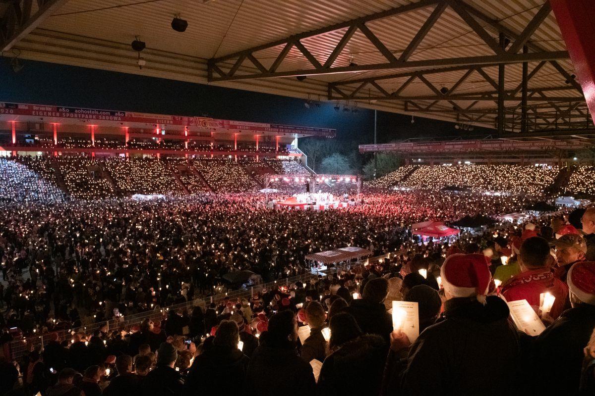 Ein Fußballstadion ist voll mit Menschen. Auch auf dem Rasen.