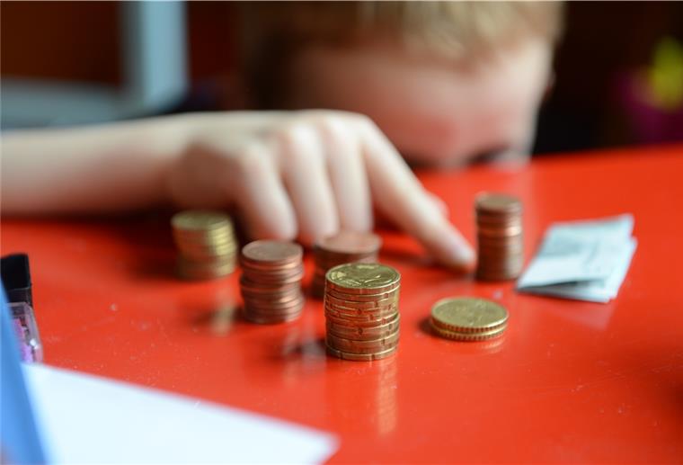 Studie: Corona verschärft Kinderarmut Ein fünfjähriger Junge sitzt an einem roten Tisch und zählt sein gespartes Taschengeld.