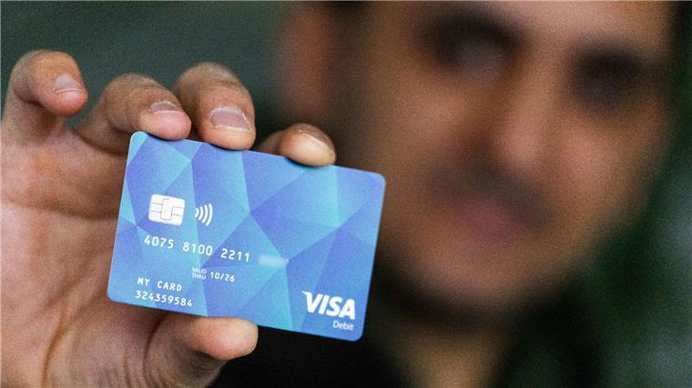Bundesweite Bezahlkarte für Flüchtlinge kommt Ein Geflüchteter hält eine Debitcard in der Hand.