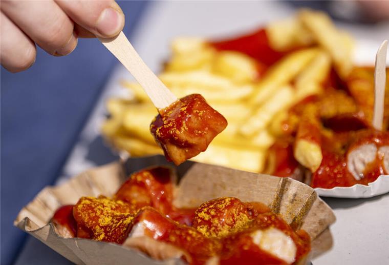 Vom Imbiss zum Kult-Snack - Doch wer hat die Currywurst eigentlich erfunden? Ein Genussmoment im Zeichen der Tradition – eine Person genießt eine Currywurst zum 75. Jahrestag ihrer Erfindung. Ein kulinarisches Kulturerbe, das deutschlandweit begeistert.