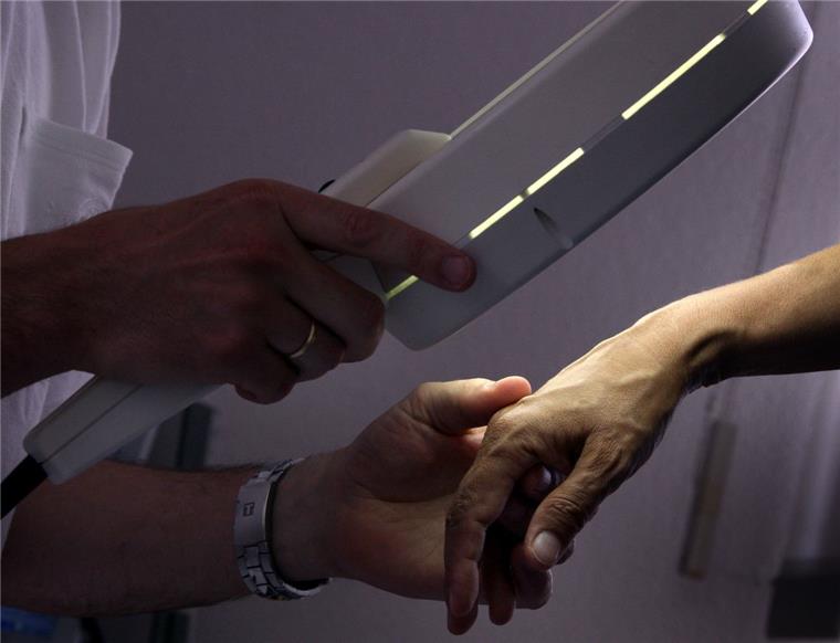Hautarzt-Mangel in Bremerhaven: Senatorin hält Poliklinik für denkbar Ein Hautarzt untersucht mit einem Vergrößerungsglas eine Patientin.