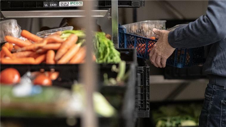 Ein Helfer legt Lebensmittel in eine Kiste.