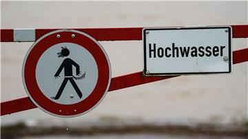 Ein Hochwasser-Schild steht an einem überfluteten Feld.