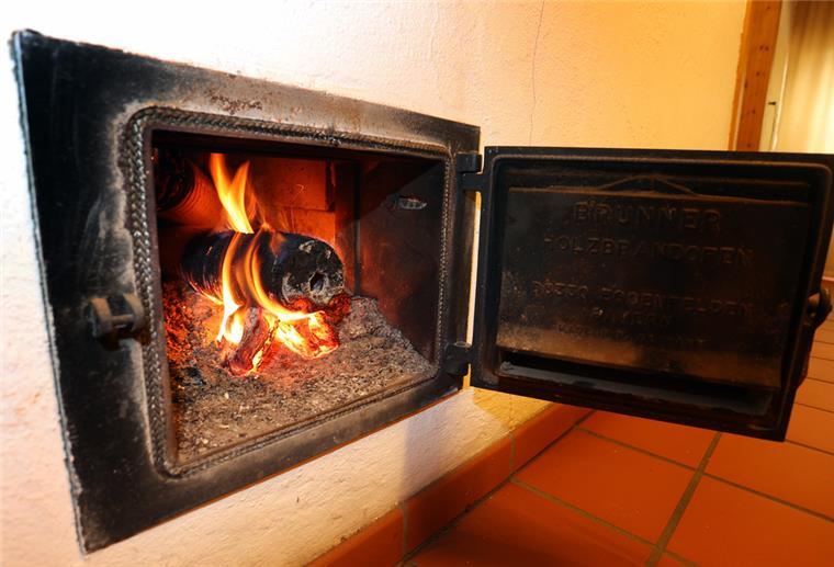 Experten warnen: Heizen mit Holz schädigt Klima und Gesundheit Ein Holzofen wird vom Hausflur aus mit Holzbriketts geheizt