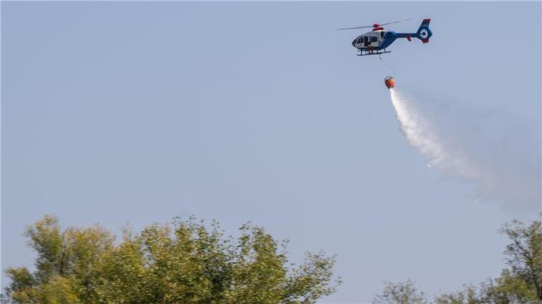Ein Hubschrauber der Polizei wirft bei einer Übung zur Waldbrandbekämpfung Löschwasser ab.