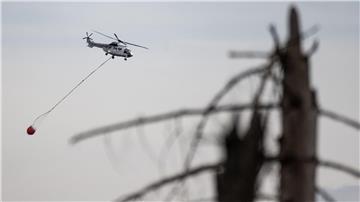 Ein Hubschrauber fliegt bei Löscharbeiten über einen Waldbrand.