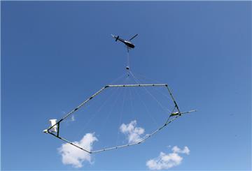 Ein Hubschrauber schleppt eine Antenne über den Grund, die nach dem SkyTEM-Verfahren den Aufbau des Untergrundes misst.
