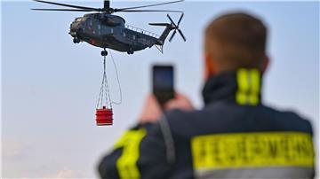 Ein Hubschrauber vom Typ Sikorsky CH-53 der Luftwaffe fliegt mit einem Wasserbehälter während einer Übung über den Flugplatz Müncheberg-Eggersdorf.