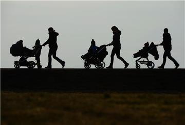  Drei Mütter schieben ihre Kinderwagen eine Landstraße entlang. 