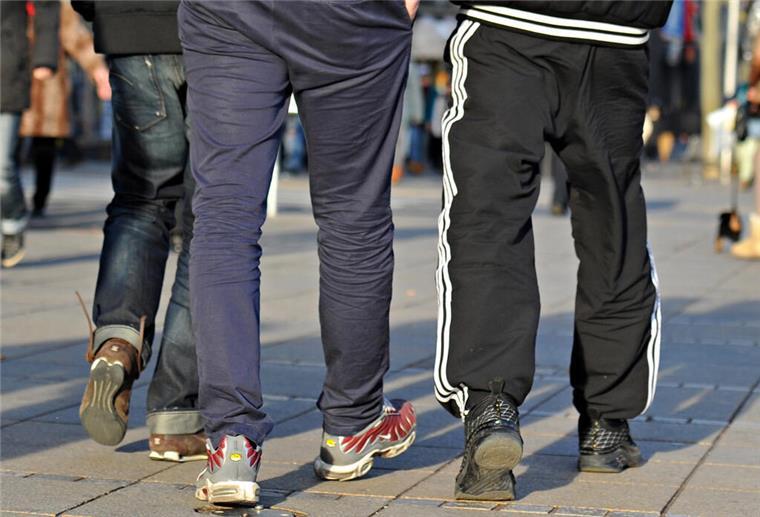 In Jogginghosen gehen junge Männer die Königstraße entlang.