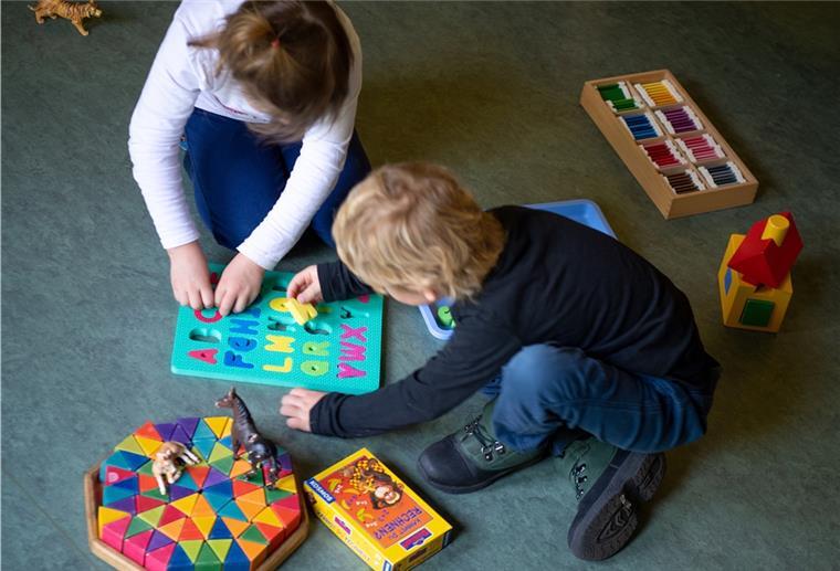 Ein Junge und ein Mädchen spielen in einem Kindergarten auf dem Boden. 