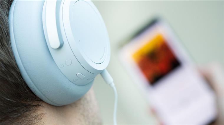 Ein junger Mann hört mit Kopfhörern Musik.