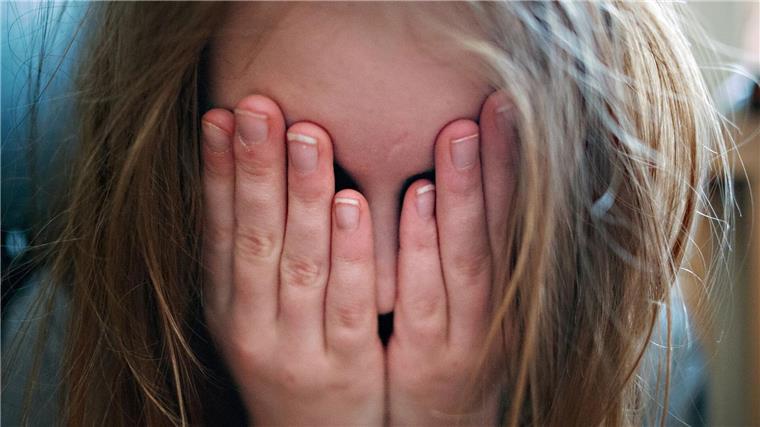Umfrage: Eltern sehen erhöhtes Stress-Level bei Kindern Ein junges Mädchen hält sich die Hände vor ihr Gesicht.