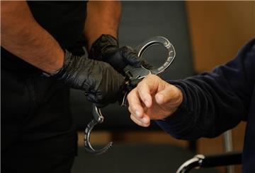 Ein Justizbeamter nimmt dem 82 Jahre alten Angeklagten in einem Saal des Landgerichts die Handschellen ab