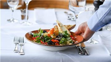 Ein Kellner serviert einen Salatteller in einem Restaurant.