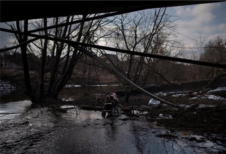 Ukraine-Krieg: Mann erfuhr über soziale Medien vom Tod seiner Familie Ein Kinderwagen steht in einer Pfütze unter einer zerstörten Brücke.