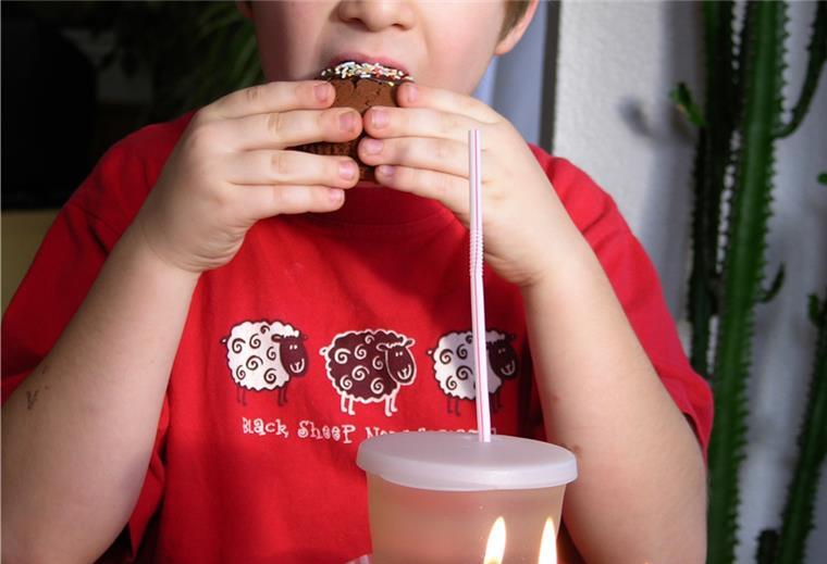 Ein kleiner Junge sitzt vor seinen Geburtstagskerzen und beißt in einen Muffin. Ab Mittwoch können Kinder im Kreis Rotenburg wieder mit Freunden feiern. 