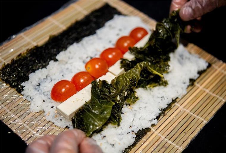 Traditionelles Gericht neu interpretiert - Grünkohl-Sushi Ein Koch bereitet in der Küche des Restaurants Moto Kitchen Sushi mit Grünkohl, Tomaten und Feta zu.