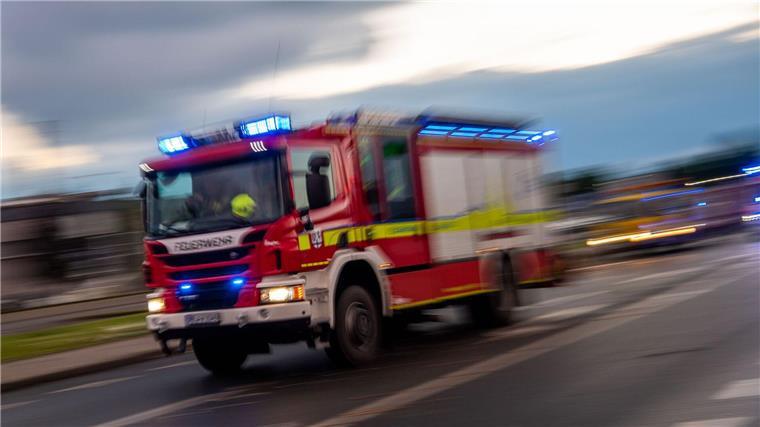 Feuer greift auf 80 Strohballen und Feld über Ein Löschfahrzeug der Feuerwehr fährt mit Blaulicht zu einem Einsatz.