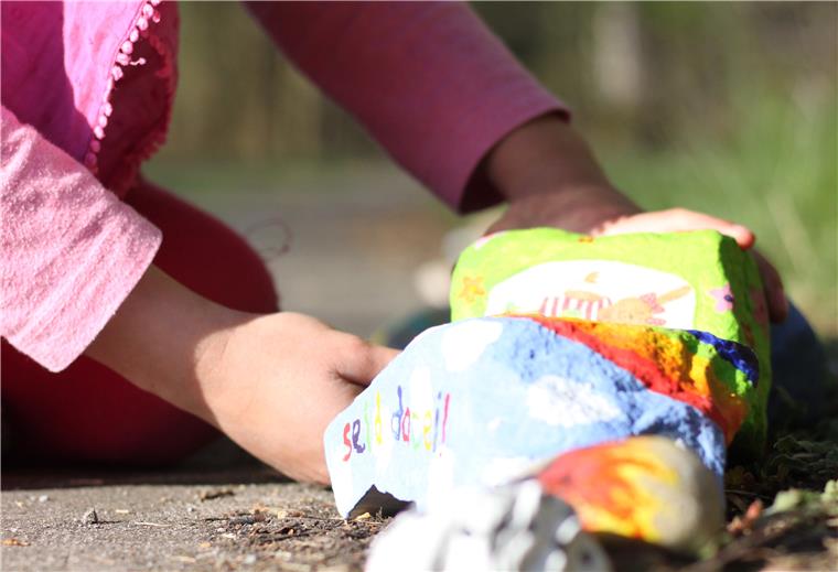 Ein Mädchen legt einen Stein in eine lange Reihe mit anderen Steinen. Paula und Lilli Heuduk aus Hepstedt haben am Ortsrand eine Steinschlange angelegt.