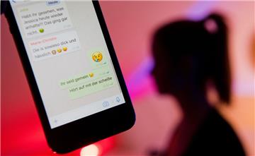 Ein Mädchen zeigt das Display eines Smartphones mit einem fiktiven Chatverlauf beim Messenger WhatsApp, in dem ein Mädchen beleidigt wird (gestellte Szene).