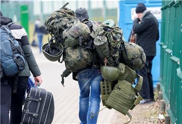 Ein Mann, der zuvor aus der Ukraine geflohen war, trägt am Grenzübergang in Medyka eine Kampfausrüstung, als er Polen verlässt, um in der Ukraine zu kämpfen.