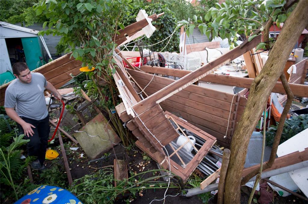 Ein Mann geht durch die Trümmer einer Gartenlaube, die durch ein schweres Unwett...