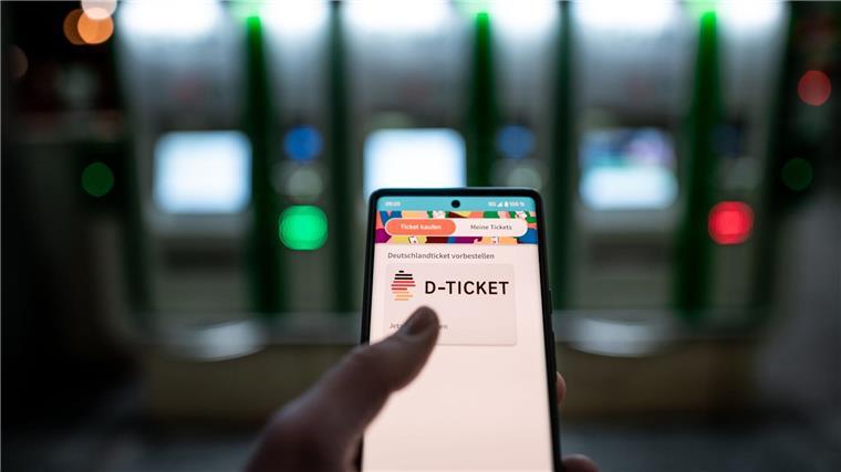 Ein Mann hält ein Mobiltelefon, auf dem das „D-Ticket“ gekauft werden kann.