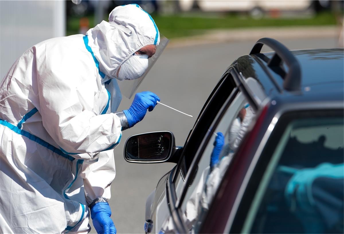 Bayern: Panne bei Corona-Tests mit 900 Infizierten Ein Mann im Schutzanzug nimmt an einem Corona-Testzentrum an der A8 an der Rastanlage Hochfelln-Nord (Bayern) einen Abstrich bei einem Autofahrer.