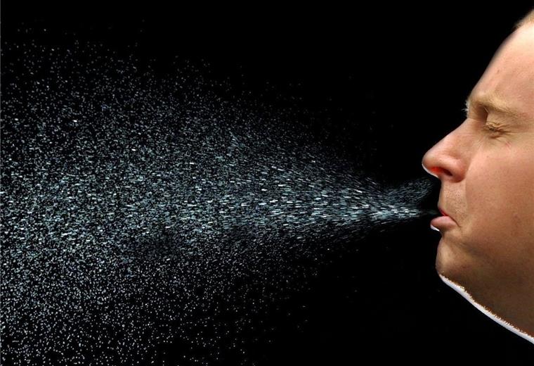 Ein Mann niest. Beim Niesen fliegen viele Tröpfchen durch die Luft. Auf diese Weise kann sich auch das neuartige Coronavirus Sars-CoV-2 verbreiten.