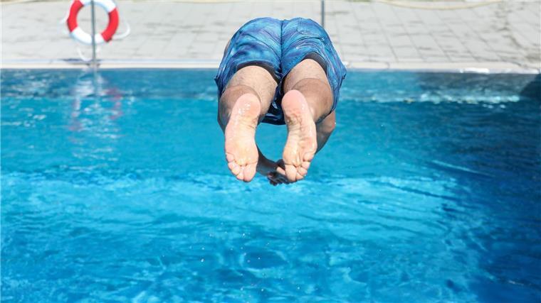 DLRG sucht Rettungsschwimmer für die Badesaison 2024 Ein Mann springt in einem Schwimmbad ins Wasser.