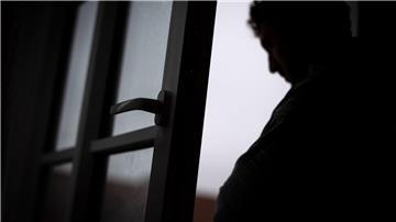 Ein Mann steht am offenen Fenster seiner Wohnung.