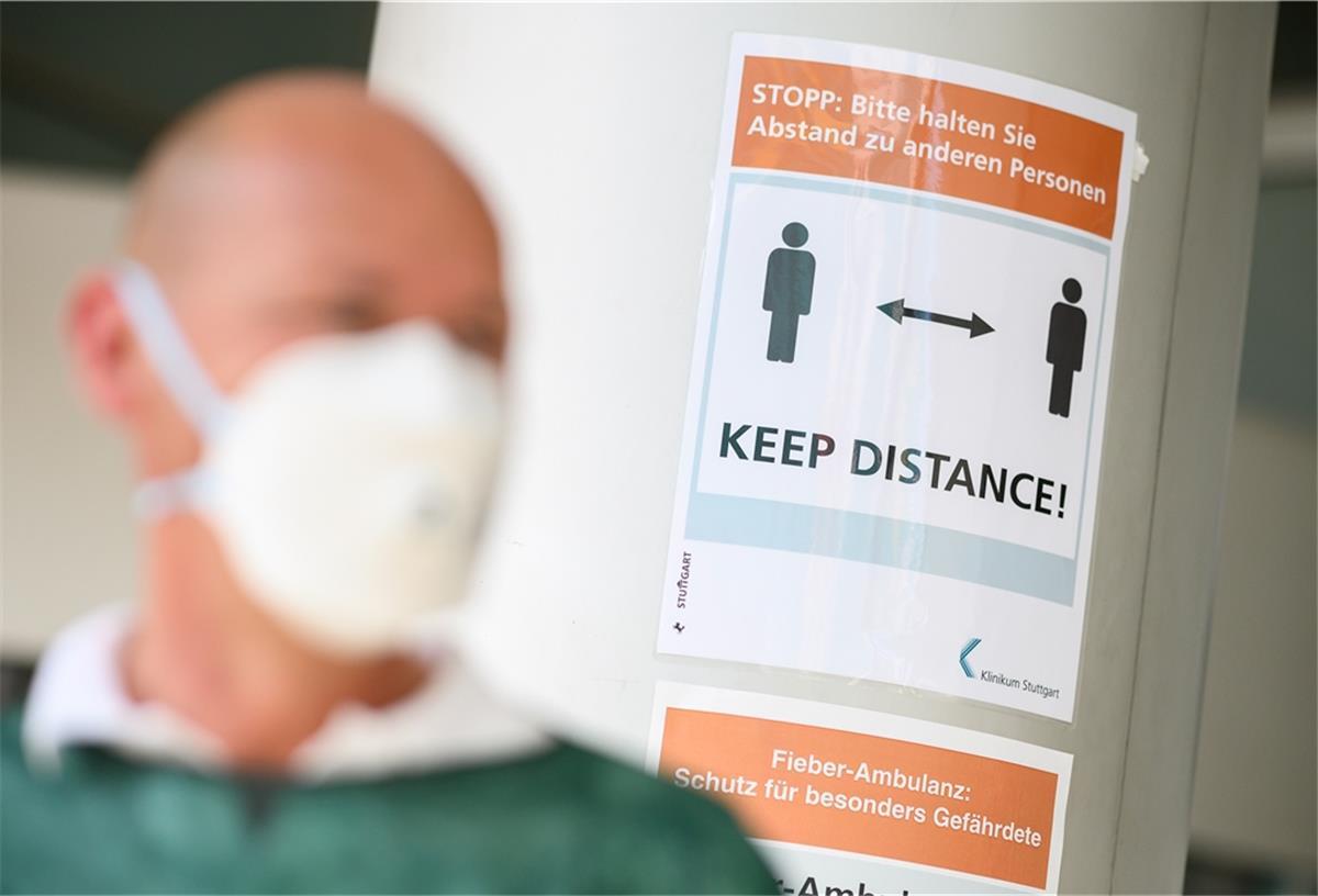 Riskogebiete: Reisen in Deutschland verboten Ein Mann steht vor einem Schild auf dem «Keep Distance» (dt. Abstand halten) steht.