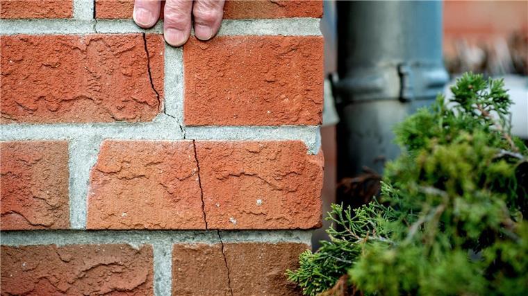 Erde bei Syke in Niedersachsen bebt Ein Mann streicht mit seiner Hand über den durch ein Erdbeben entstanden Riss am Haus.