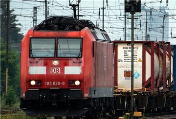 Eine Lok zieht einen Güterzug unter einem Gewirr aus Oberleitungen und Signalen.